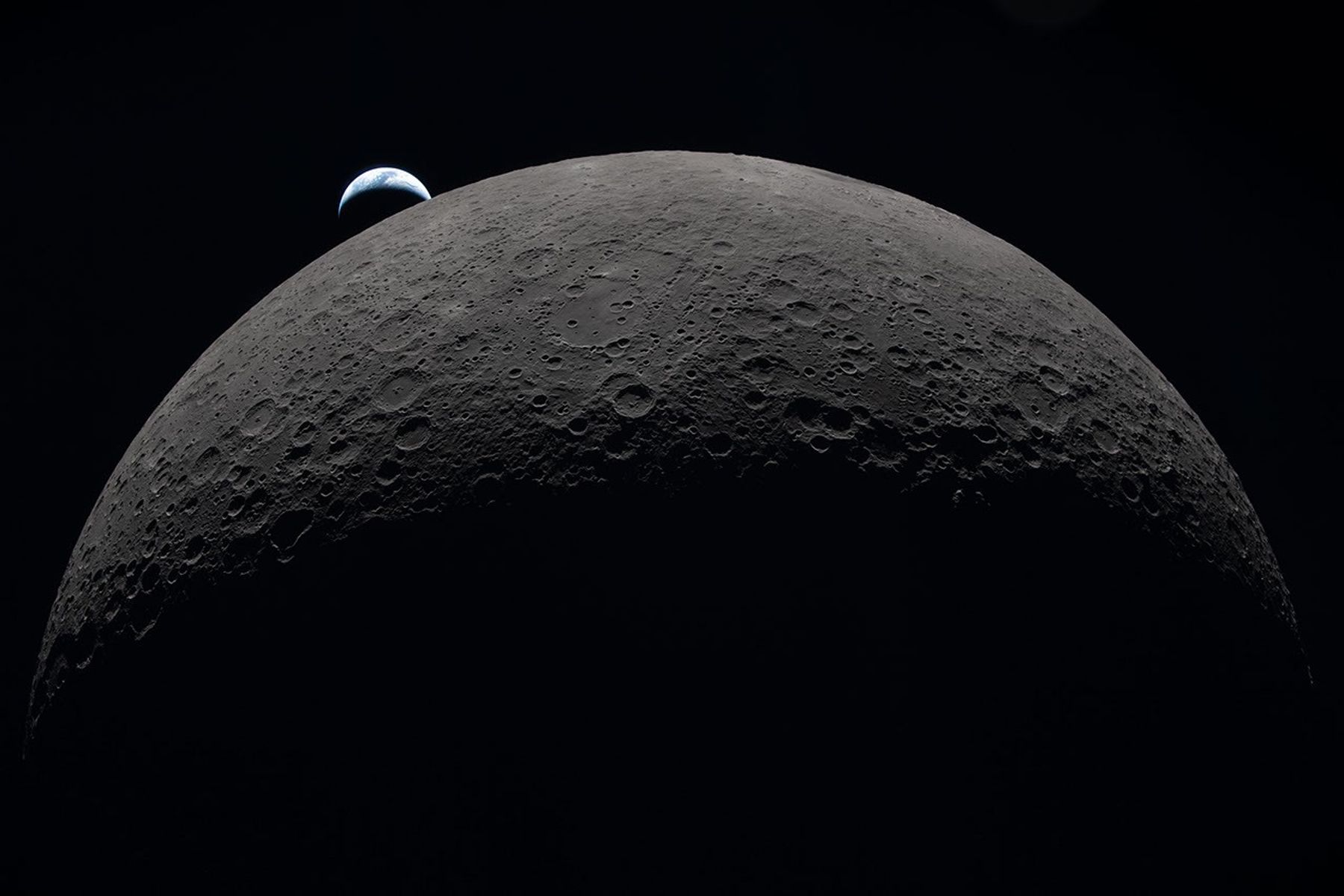La Tierra parcialmente iluminada se oculta tras el horizonte lunar, fotografiada desde Artemis II